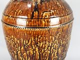 un vase brun posé sur une surface blanche