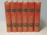 six livres rouges alignés sur une surface blanche