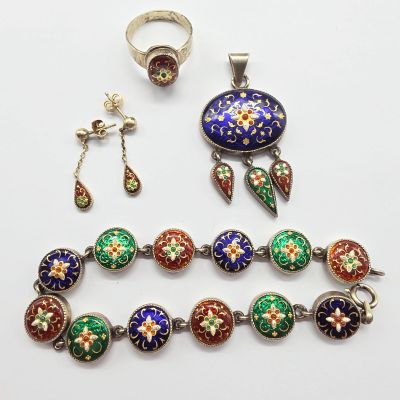 un gros plan d'un collier, d'une bague et d'un bracelet posés sur une surface blanche