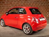 a small red car parked in front of a brick wall