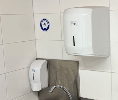 un distributeur de papier essuie-tout blanc fixé au mur au-dessus d'un lavabo