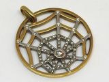 une image représentant un pendentif en or et en argent orné d'une toile d'araignée