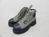 green boots with black soles and black soles on a white surface