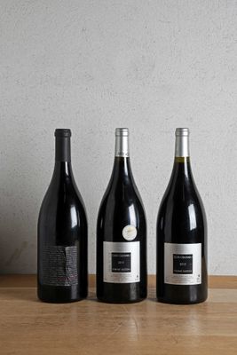 three bottles of wine are lined up on a wooden table