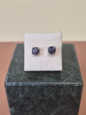a pair of blue sapphire stud earrings sitting on top of a white cloth