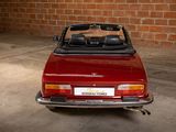 an image of a red convertible car parked in front of a brick wall