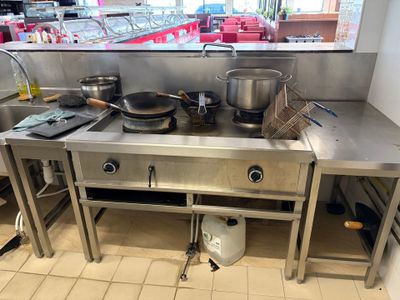 un plan de travail en acier inoxydable sur lequel sont posés des casseroles et des poêles, dans une cuisine professionnelle