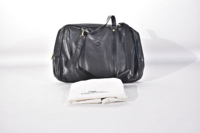 un sac à main en cuir noir posé à côté d'une serviette pliée sur une surface blanche