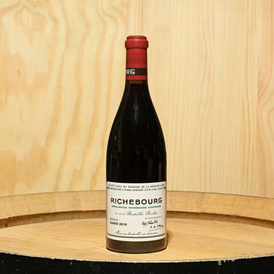 a bottle of wine sitting on top of a barrel