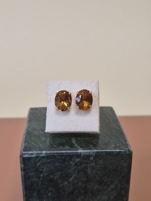 une paire de boucles d'oreilles en saphir jaune posées sur un bloc de marbre