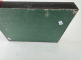 a green suitcase sitting on a white surface with a sticker on it