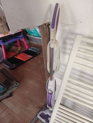purple and white steam mop sitting on a tiled floor next to a white radiator