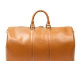 un sac de voyage en cuir marron posé sur une surface blanche