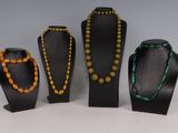 Trois colliers et deux bracelets sont exposés dans une vitrine.