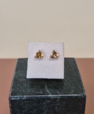 une paire de boucles d'oreilles en or posée sur un bloc de marbre