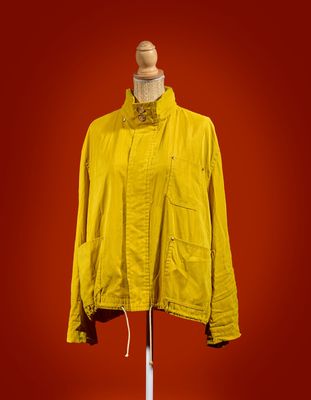 a yellow jacket on a mannequin stand against a red background