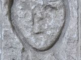 une sculpture en pierre représentant le visage d'un homme, sur la façade d'un immeuble