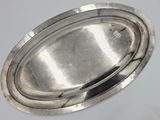 an oval silver plate on a white surface with a silver rim