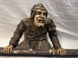 une statue représentant un homme assis sur un tuyau