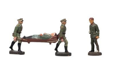 three figurines of soldiers carrying a man on a stretcher