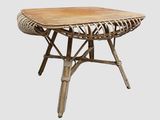 La table est en bois et présente un motif en rotin.