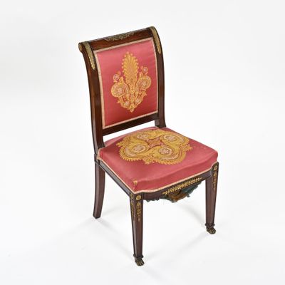 une image représentant une chaise dont l'assise est recouverte d'un tissu rouge et or