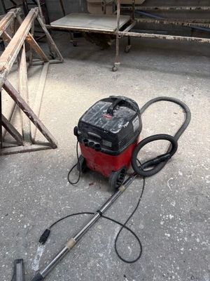 un aspirateur rouge et noir posé par terre dans un garage