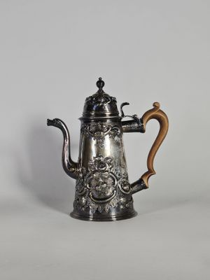 une cafetière en argent avec une poignée en bois sur une surface blanche
