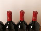 three bottles of red wine are lined up on a wooden table