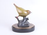 sculpture of a bird perched on a tree branch on a white background