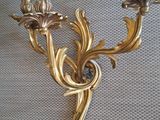 brass wall sconce with two candle holders on a wall