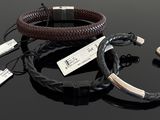 two leather bracelets on a table with tags on them