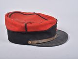 an old red and black hat sitting on top of a white table