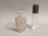 a small glass and a small glass bottle on a table