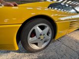 yellow sports car parked in a garage with a person standing next to it
