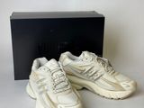 a pair of white sneakers in front of a black box