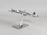 maquette métallique argentée d'un avion posée sur un socle, sur une surface blanche
