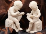 two figurines of children sitting on a bench