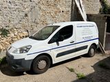 une camionnette blanche garée devant un mur de pierre