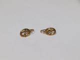 une paire de boucles d'oreilles en or sur une surface blanche