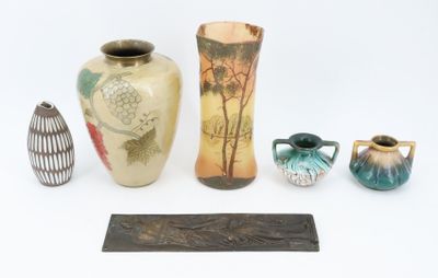 four vases and a plaque on a white surface
