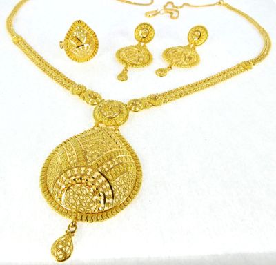 a close up of a gold necklace and earrings on a white surface