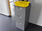 a yellow trash can sitting on top of a gray filing cabinet