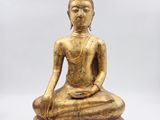 une statue de Bouddha en or assise au sommet d'une pile de livres