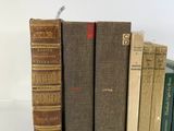 several old books are lined up in a row on a white surface