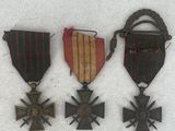 three medals and a cross are sitting on a white surface