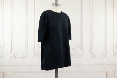 une robe noire posée sur un mannequin contre un mur blanc