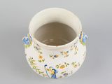 a small white vase with blue and yellow flowers on it