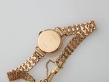an image of a gold wrist watch with a chain around it