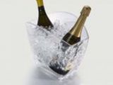 des bouteilles de champagne dans de la glace, dans un saladier en verre posé sur un plan de travail blanc